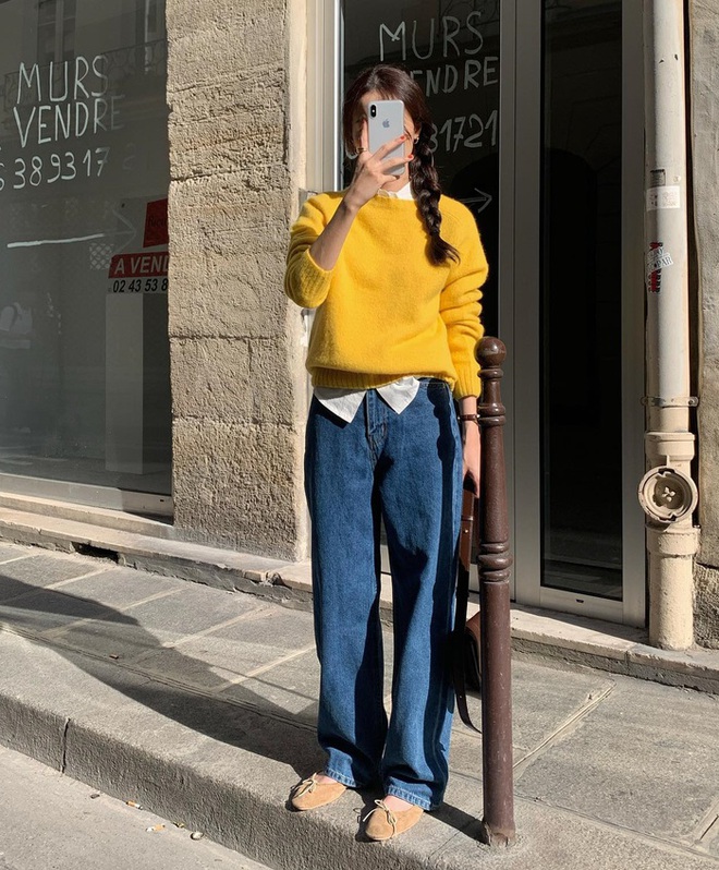 Áo len vàng ấm phối cùng quần jeans xanh đậm tạo nên sự kết hợp thú vị. Lớp sơ mi trắng bên trong đóng vai trò cân bằng sắc độ, giúp outfit không bị quá chói. Đây là minh chứng rằng màu sắc tươi sáng hoàn toàn có thể xuất hiện ở môi trường làm việc, miễn là được tiết chế thông minh.