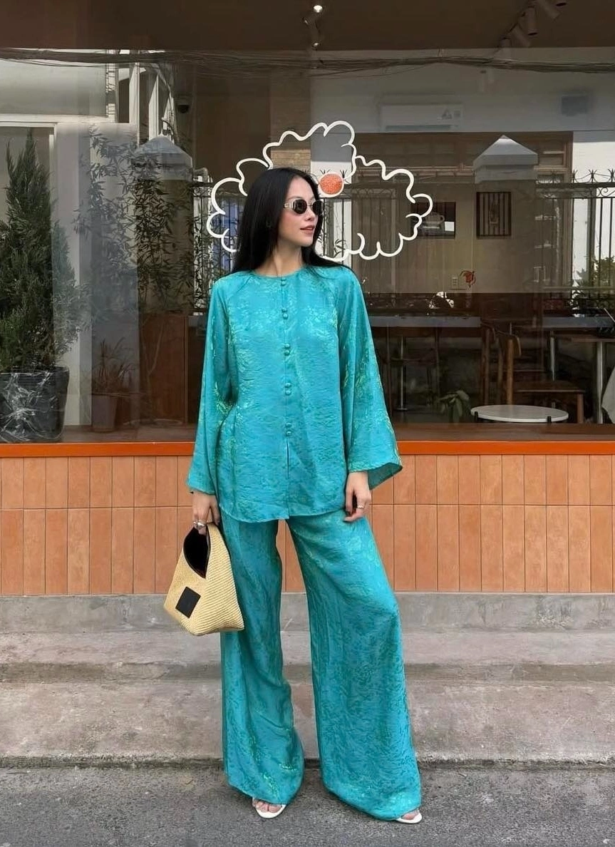 Phiên bản áo bà ba màu xanh da trời dịu nhẹ, dáng suông, tay loe mềm mại. Khi kết hợp cùng quần lụa rộng và phụ kiện tối giản, bộ trang phục toát lên vẻ trang nhã, hiện đại. Đây là lựa chọn lý tưởng cho những ai yêu thích phong cách tối giản nhưng vẫn muốn giữ bản sắc truyền thống trong ngày Tết.