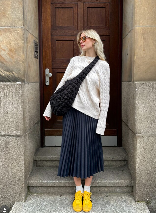 Tông kem và xanh navy chiếm phần lớn tổng thể set đồ, tạo vẻ thanh lịch và nền nã. Giày vàng trở thành điểm nhấn nổi bật, giúp bộ trang phục bớt đơn điệu và thu hút ánh nhìn.