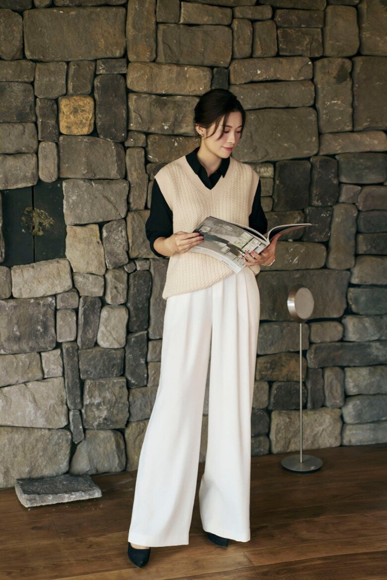 Bộ trang phục khai thác sự tương phản chất liệu một cách tinh tế. Áo gile len dệt mang lại cảm giác mềm mại, ấm áp, kết hợp cùng sơ mi vải mịn tạo lớp nền gọn gàng. Phía dưới, quần ống rộng chất liệu suông nhẹ giúp tổng thể trở nên thanh thoát, tạo sự cân bằng giữa mềm mại và cấu trúc.