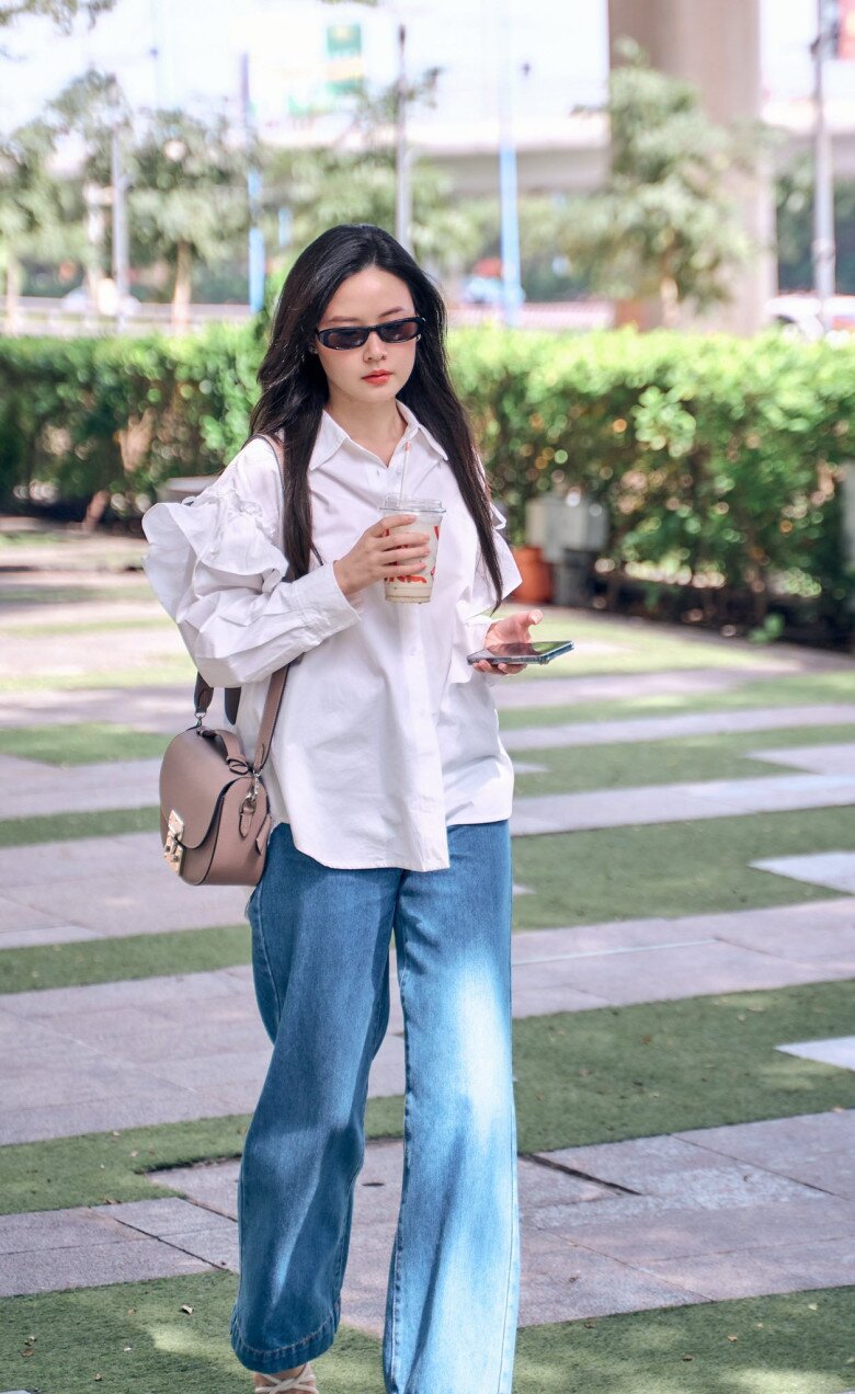 Sơ mi trắng tay phồng phối cùng quần jeans ống rộng tạo nên bản phối smart-casual chuẩn mực cho cô giáo Midu. Việc không sơ vin áo giúp tổng thể vừa năng động vừa đủ thanh lịch cho môi trường làm việc sáng tạo lại có thể giấu bụng mỡ.