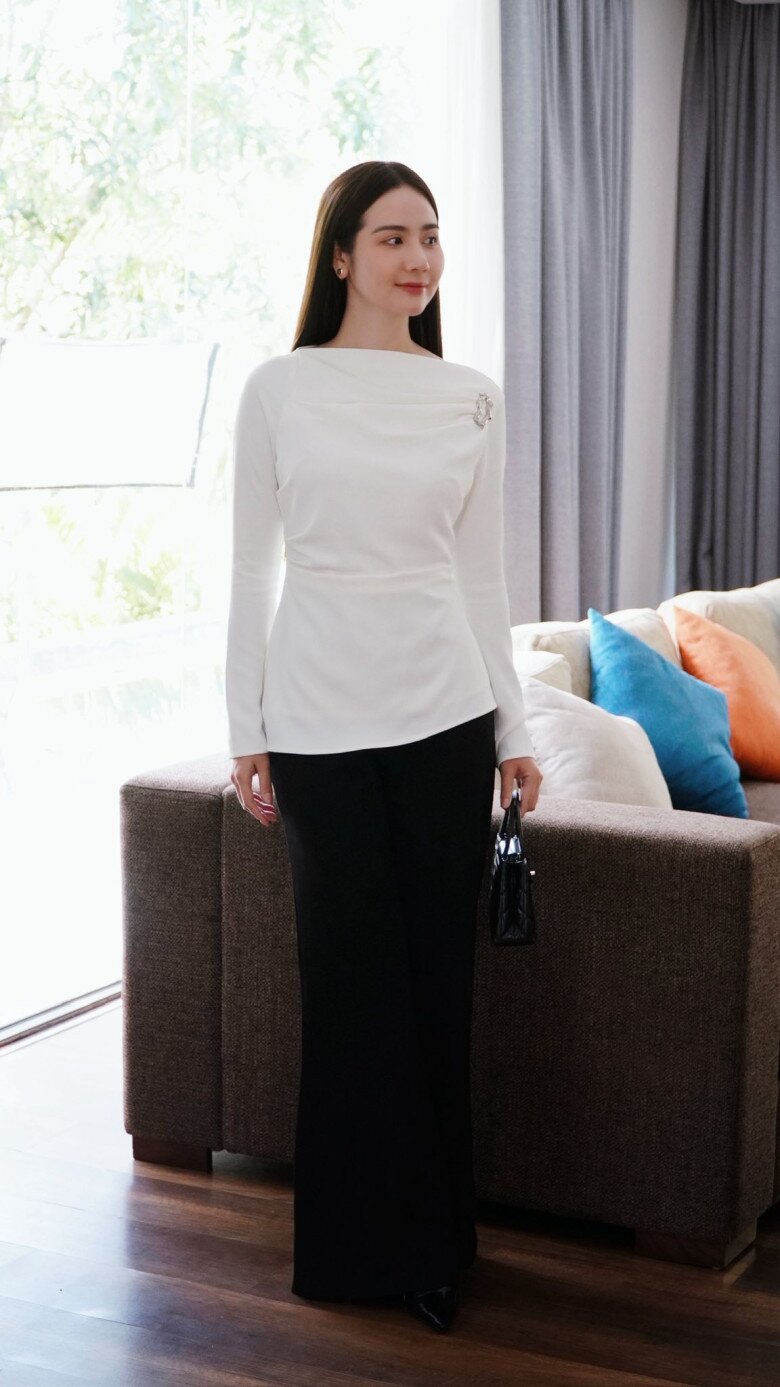 Áo trắng dáng ôm với phần nhấn eo giúp phân chia tỷ lệ cơ thể hài hòa, tạo cảm giác thon gọn. Diễn viên Huyền Lizzie tinh tế kết hợp quần đen ống suông là lựa chọn an toàn nhưng không hề nhàm chán. Bảng màu tương phản kinh điển làm nổi bật thần thái điềm tĩnh, chuẩn hình ảnh quý cô công sở yêu sự tối giản.