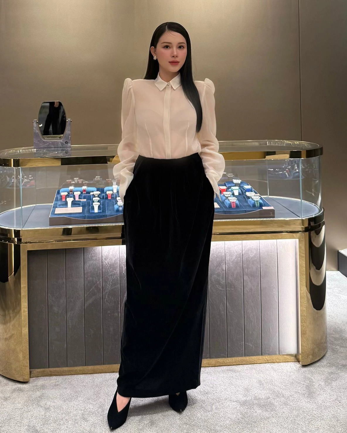 Sơ mi lụa xuyên thấu nhẹ phối chân váy dài đen tạo nên sự cân bằng giữa mềm mại và quyền lực. Thiết kế vai phồng và phom suông dài mang hơi hướng high-fashion, lý tưởng cho môi trường công sở yêu cầu sự tinh tế và đẳng cấp.