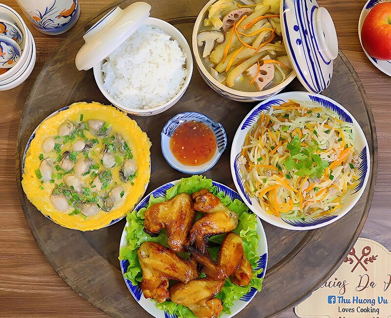 Mâm cơm này gồm các món: Trứng tráng hàu, canh củ sen hầm nấm thập cẩm, cánh gà nướng mật ong, su hào xào.