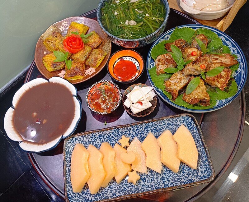 Mâm cơm nhà gồm có: - Canh rau khoai lang - Nem cua bể - Chè đỗ đen - Cá lăng nướng riềng - Tráng miệng dưa vàng. (Ảnh: Thùy Duyên)