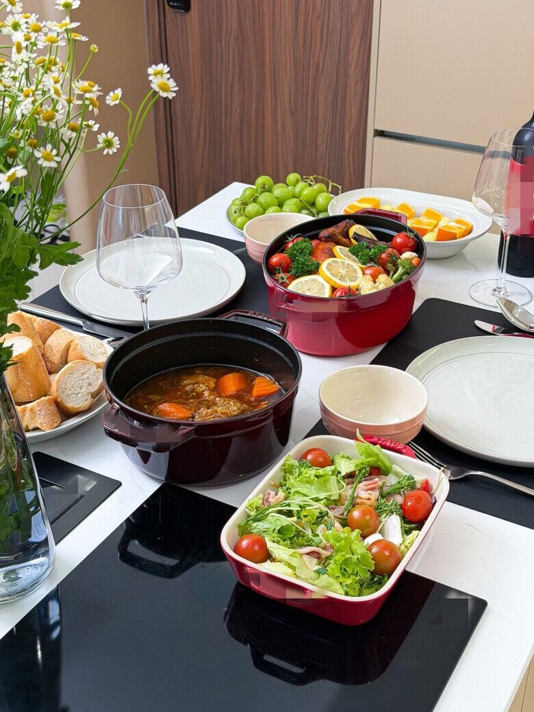 Bàn tiệc thịnh soạn với món gà nướng rau củ, súp cà rốt và salad tươi ngon. Mọi món ăn đều được bày biện chỉn chu trong chính những chiếc nồi, khay nướng sang trọng.