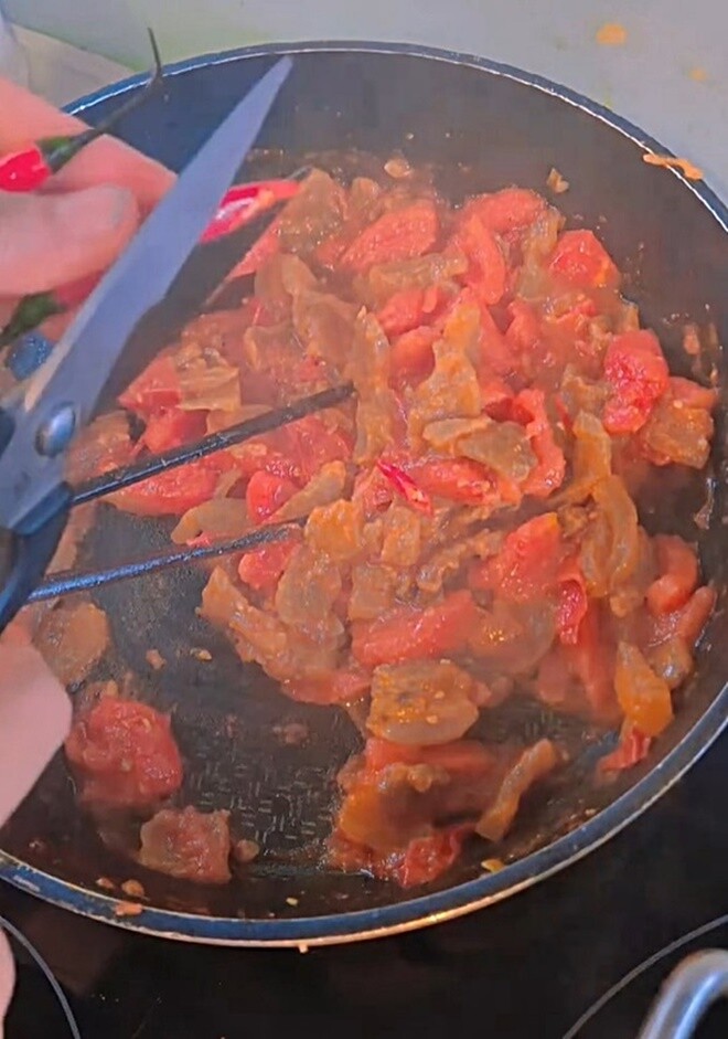 Để món ăn thêm cứu cánh cho ngày mưa rét, Phương Phạm dùng kéo cắt thêm vài lát ớt tươi trực tiếp vào chảo để tạo vị cay nồng kích thích.
