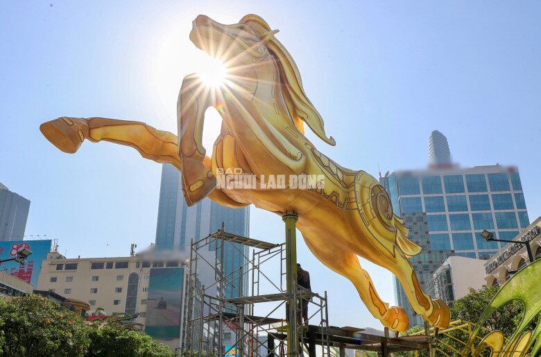 Tại khu vực cổng chào đường hoa, linh vật Bính Ngọ đang dần hoàn thiện. Mô hình cao gần 7 m, dài khoảng 9 m, tạo hình tư thế tung vó, thân phủ sắc vàng rực, nổi bật trên phố đi bộ Nguyễn Huệ.