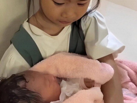 Xôn xao cảnh bé gái 6 tuổi xinh xắn ngồi ôm đứa bé sơ sinh ở hành lang bệnh viện, đau lòng chuyện phía sau
