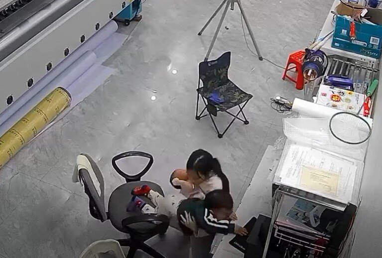 Cô nhóc dùng một tay bế em út, một tay đỡ em trai.