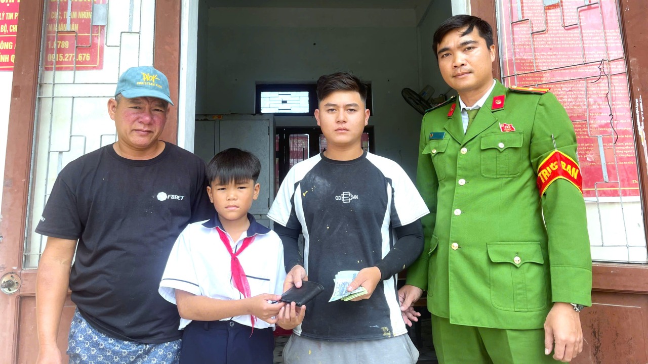 Em Nguyễn Nhật Thành cùng bố trao trả chiếc ví nhặt được cho chủ nhân đánh rơi. Ảnh: Quốc Hưng