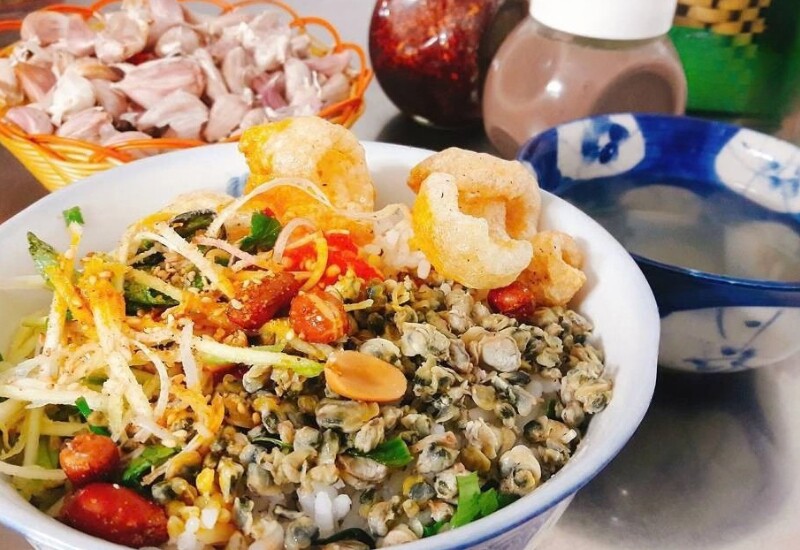 Cơm hến là món ăn dân dã gắn liền với đời sống người Huế, kết hợp hến xào đậm đà cùng cơm nguội, rau sống, tóp mỡ và mắm ruốc. Tất cả tạo nên hương vị vừa mộc mạc, vừa tinh tế, ăn hoài không chán. Hến cũng là món đặc sản được ví là “lộc trời” ở vùng đất này. 