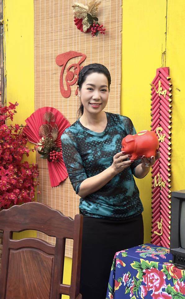 Một góc tường mành tre treo liễn đỏ mừng Tết rực rỡ, bên cạnh là mô hình pháo dây truyền thống và chú heo đất đỏ thắm mang ý nghĩa sung túc.