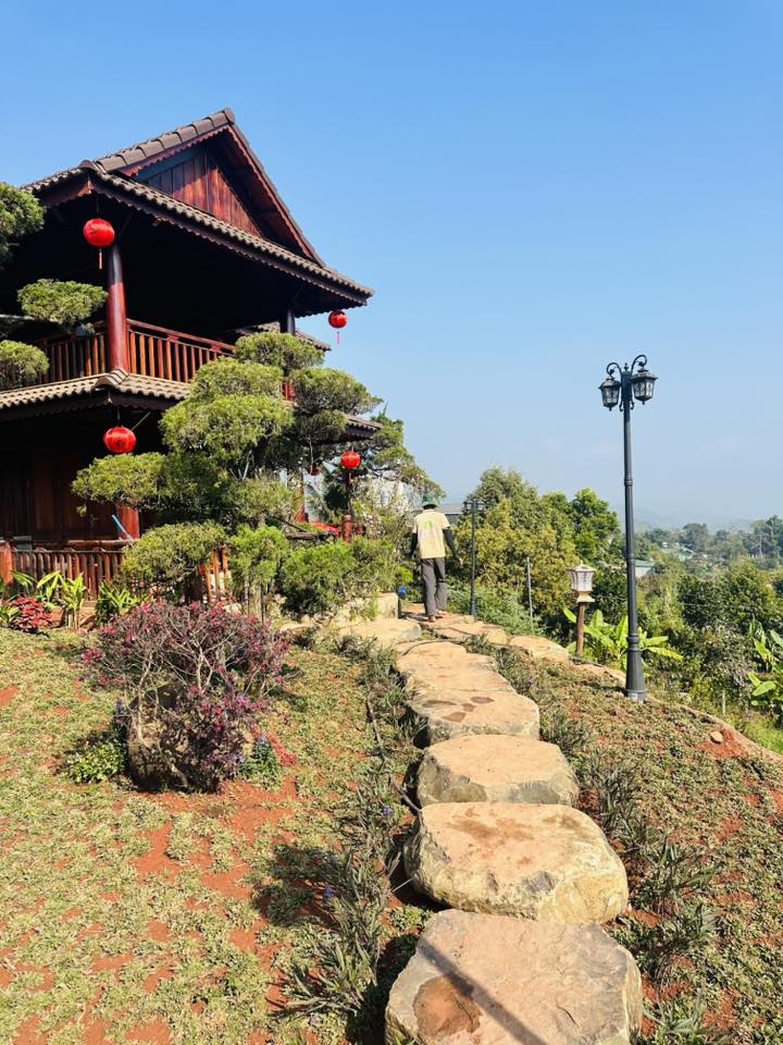 Những bậc thang bằng đá thô mộc dẫn lối lên nhà, xen kẽ là các loại hoa rực rỡ. Hệ thống đèn sân vườn được bố trí tinh tế, khiến toàn bộ cơ ngơi lung linh như một resort 5 sao vào buổi tối.