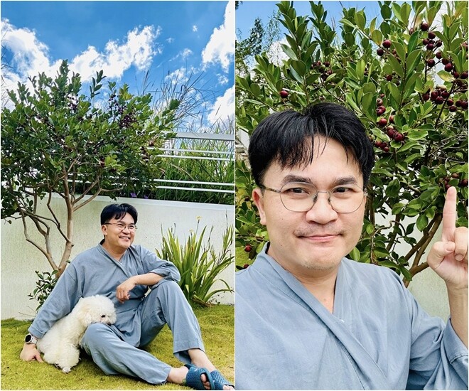 MC Đại Nghĩa rạng rỡ bên cạnh cây ổi xiêm nhỏ gọn nhưng đầy quả trong sân nhà. Những chùm quả sai trĩu, làm nổi bật sắc màu rực rỡ của khu vườn sau Tết.