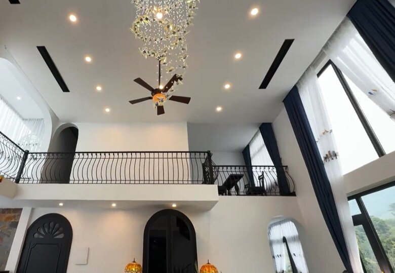 Kiến trúc thông tầng mang lại sự thoáng đãng tuyệt đối, điểm xuyết bằng chiếc quạt trần đen và hệ đèn chùm pha lê uốn lượn mềm mại như dải lụa.