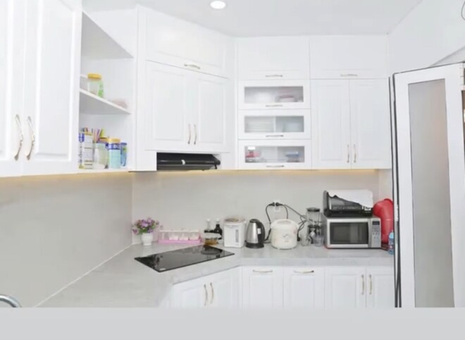 Khu vực bếp hiện đại với hệ tủ trắng tinh khôi, được trang bị đầy đủ các thiết bị gia dụng thông minh, phục vụ nhu cầu nội trợ hàng ngày.