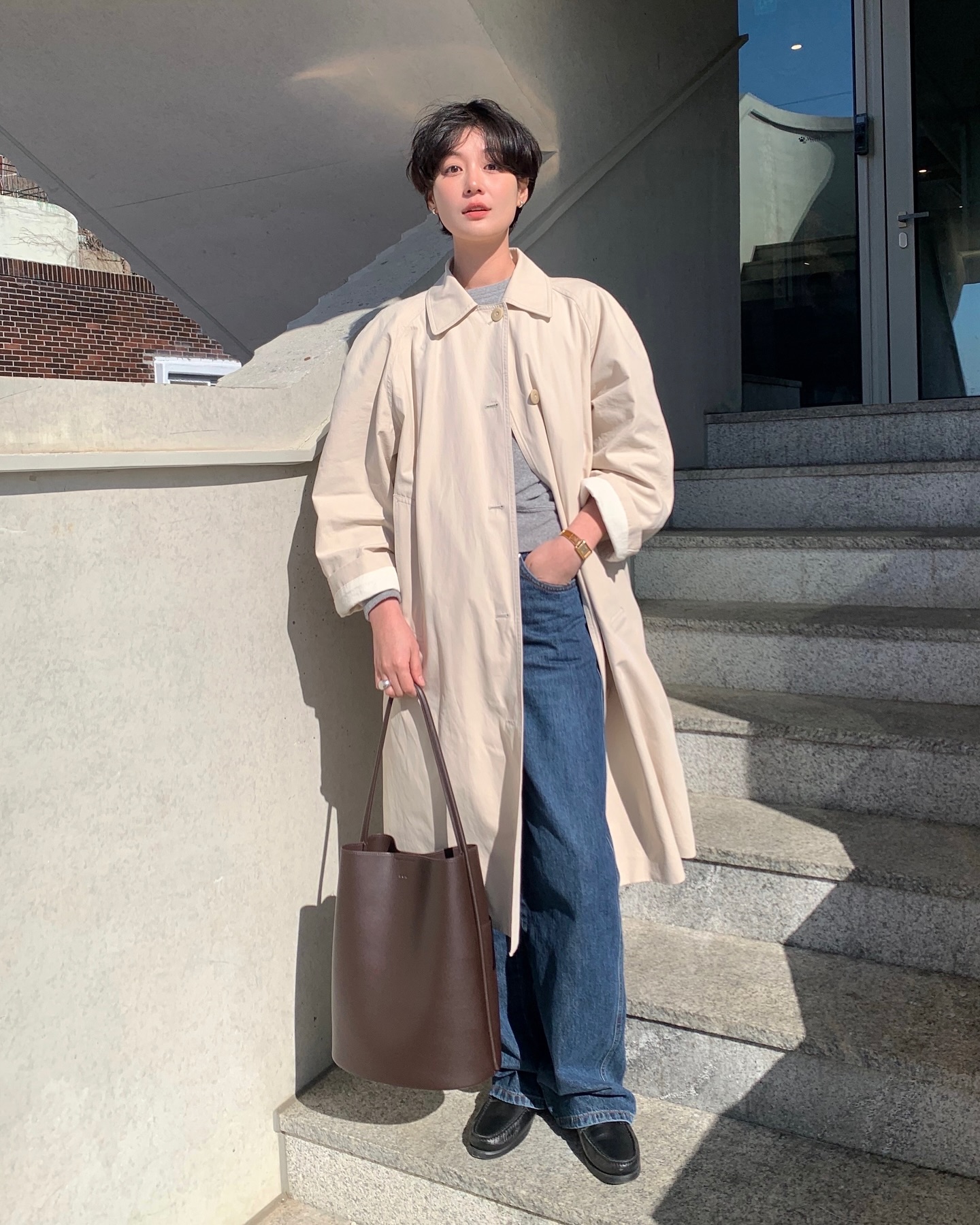 Áo trench coat là lựa chọn cân bằng giữa thanh lịch và trẻ trung khi phối cùng quần jeans. Thiết kế cổ điển, phom dáng chuẩn giúp trang phục trông tinh tế. Trench coat dễ mặc đi làm lẫn dạo phố, mang lại vẻ ngoài sành điệu mà không quá phô trương.