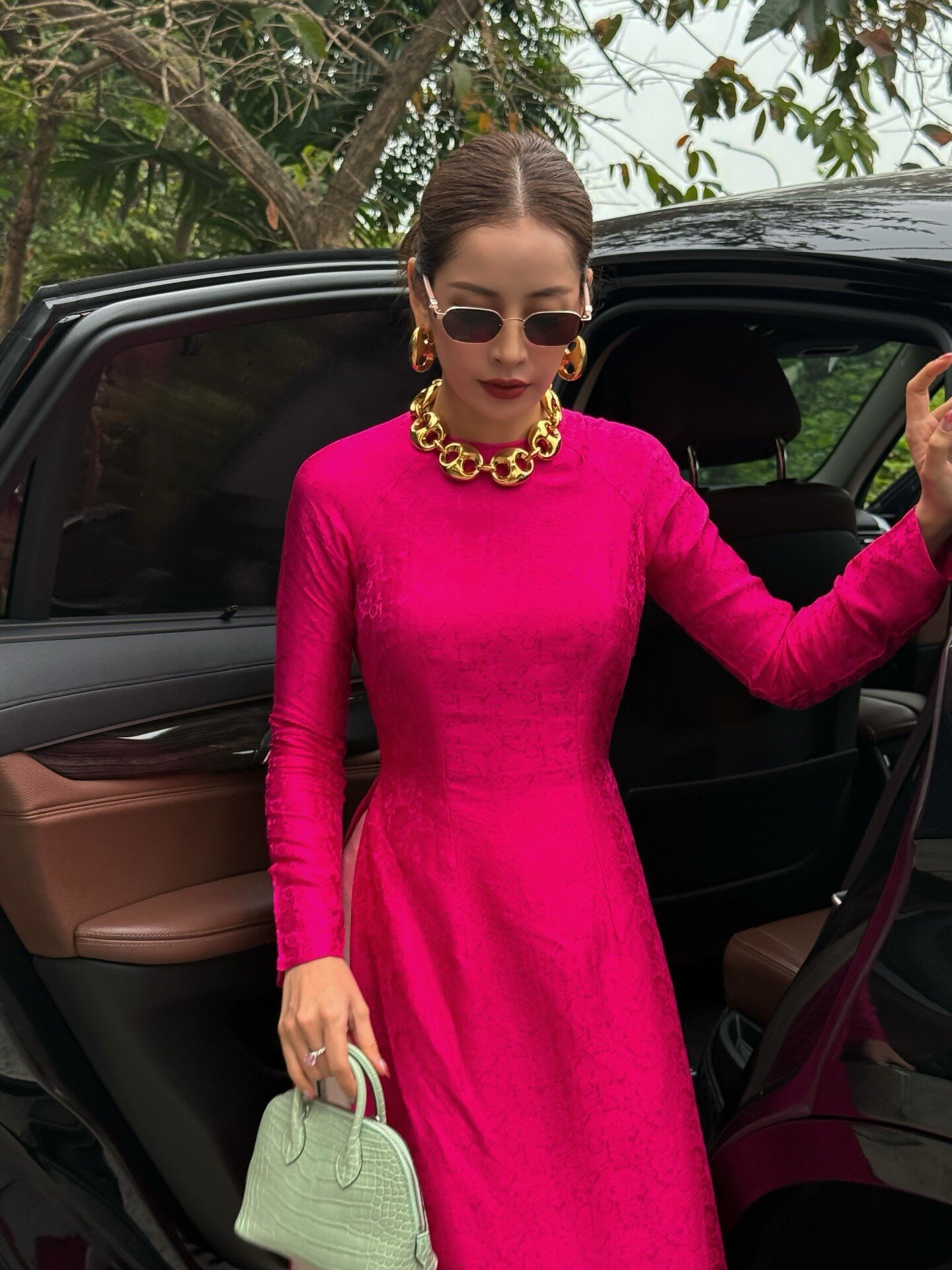 Nhưng bộ áo dài thứ 3 mới giúp Chi Pu gây bùng nổ. Cô chọn trang phục từ vải gấm màu hồng đậm, kiểu dáng ôm vừa vặn khoe vòng eo nhỏ xíu, bờ vai mảnh mai. Chi Pu búi tóc cao, đeo kính râm càng thêm phần sang trọng.