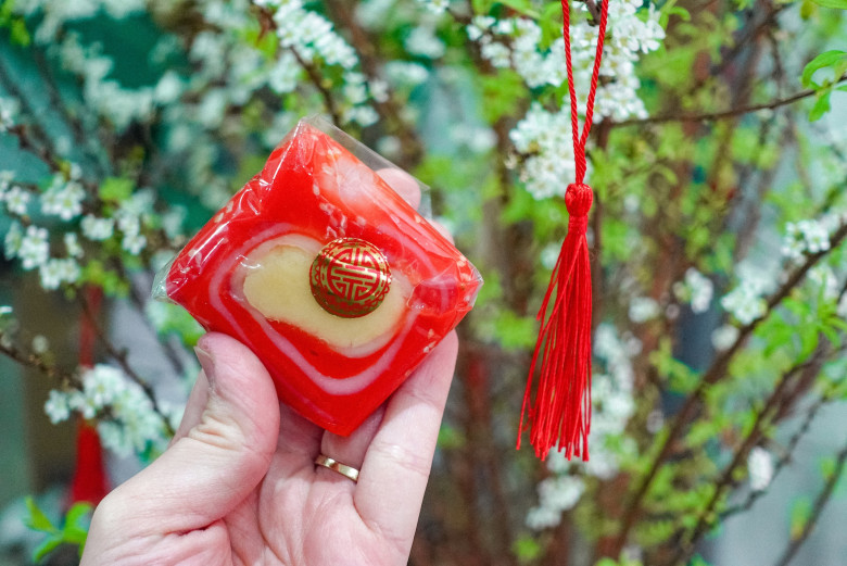 Bánh bác dẻo thơm mùi nếp, gấc đỏ quyện đậu xanh bùi ngọt. Lớp vừng bên ngoài tăng vị béo, tạo cảm giác tròn vị.