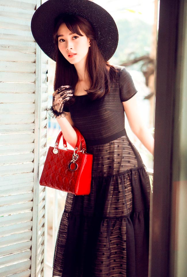 Cùng với gam màu đen cuốn hút, hoa hậu chọn phụ kiện ăn ý là mũ đen rộng vành và túi xách quý cô Dior màu đỏ.
