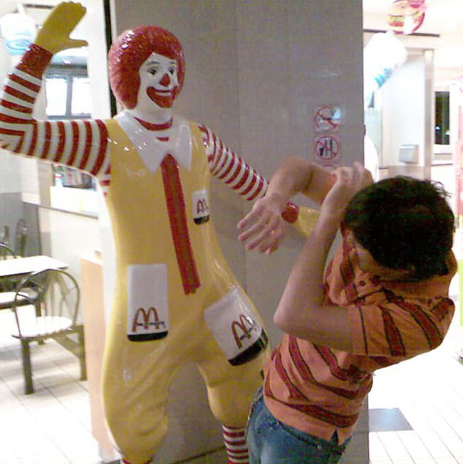 Khách hàng tỏ vẻ sợ hãi khi đứng trước tượng chú hề Ronald McDonald đang giơ tay trong một nhà hàng McDonald.
