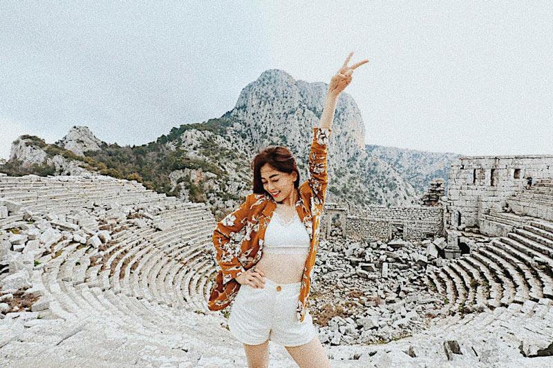 Á hậu Phương Nga khoe eo thon trước di tích cổ xưa trên đỉnh núi ở thành phố Antalya. Cô diện crop top và short trắng cũng không quên điểm tô bằng chiếc blazer hoạ tiết hoa đẹp mắt. 
