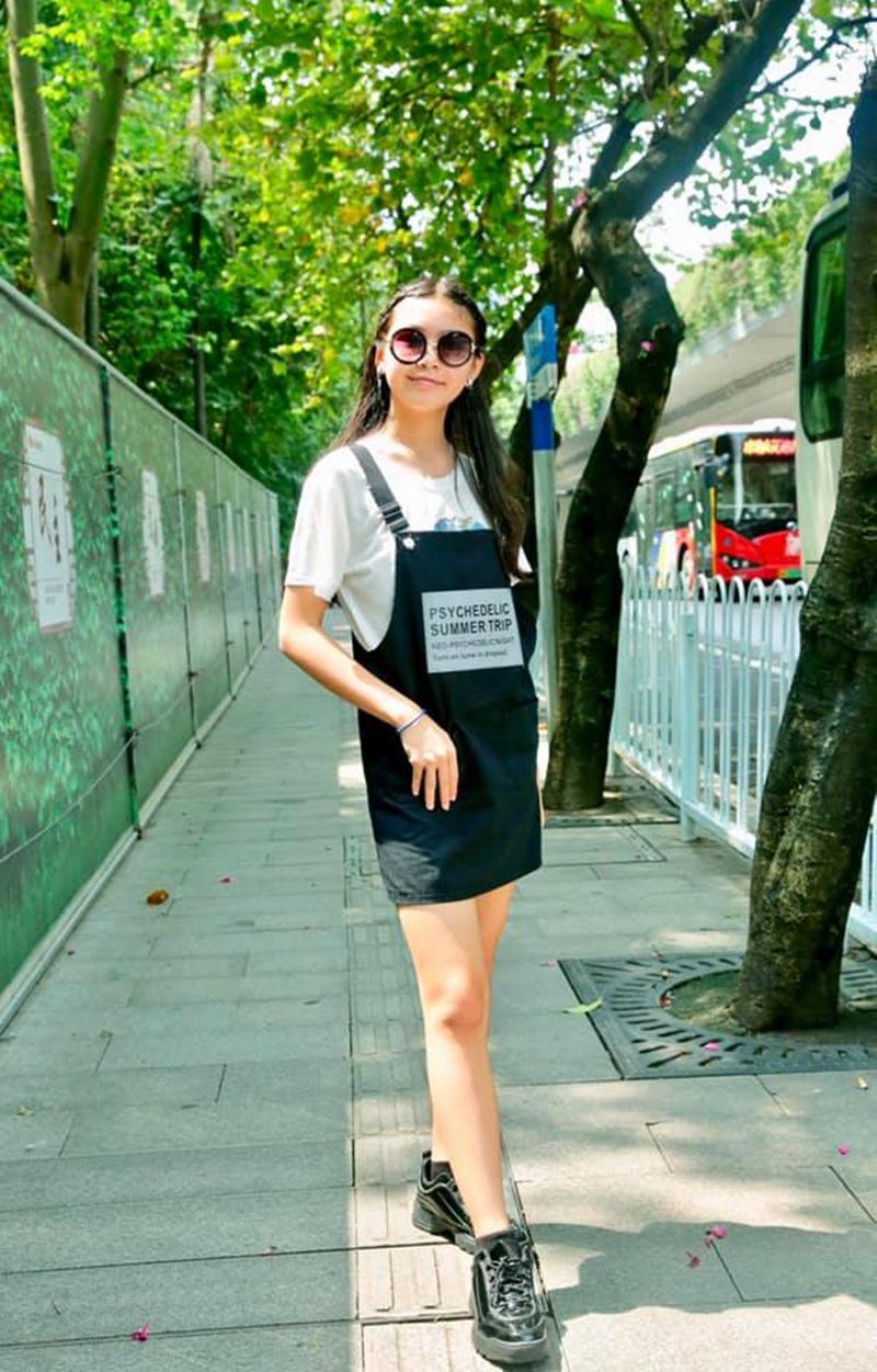 Khi dạo phố cùng gia đình, Thảo Linh luôn xuất hiện với những trang phục đơn giản nhưng không kém phần thời trang. Chân váy yếm đen phối hợp nhuần nhuyễn với T-shirt trắng, giúp cô bé vừa nổi bật nhưng vẫn năng động phù hợp với độ tuổi 14 của mình.
