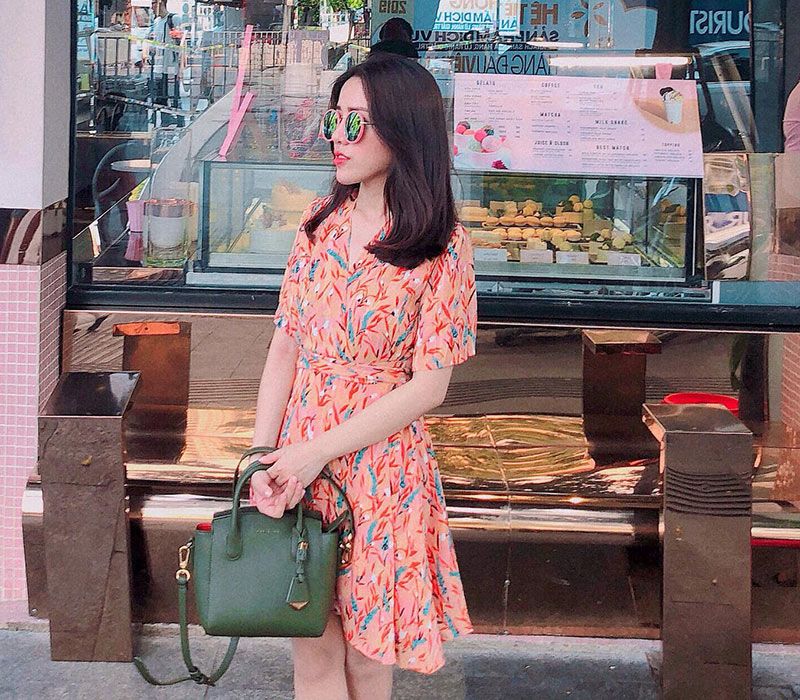Váy hoa li ti của nàng thơ mang sắc màu cam tươi tắn phù hợp với ngày hè đầy nắng. Công thêm chiếc túi xanh rêu mang lại sự hài hoà nhưng đầy ấn tượng. 
