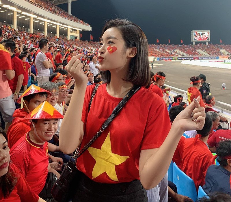 Hoa hậu Đỗ Mỹ Linh khai màn cổ vũ với bức ảnh diện áo cờ đỏ sao vàng mix kèm quần jeans đen, cô xách thêm túi Chanel lúc đi xem ĐT Việt Nam còn đá trong thời buổi chưa có dịch bệnh để động viên các cầu thủ.
