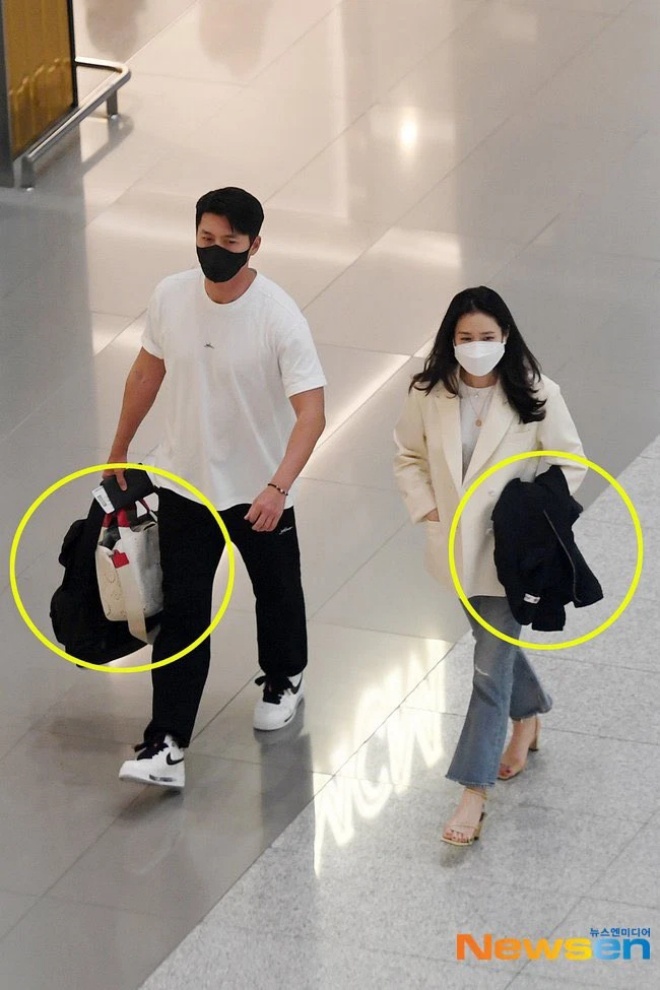 Hyun Bin cầm túi xách cho vợ trong khi Son Ye Jin giữ áo cho chồng.