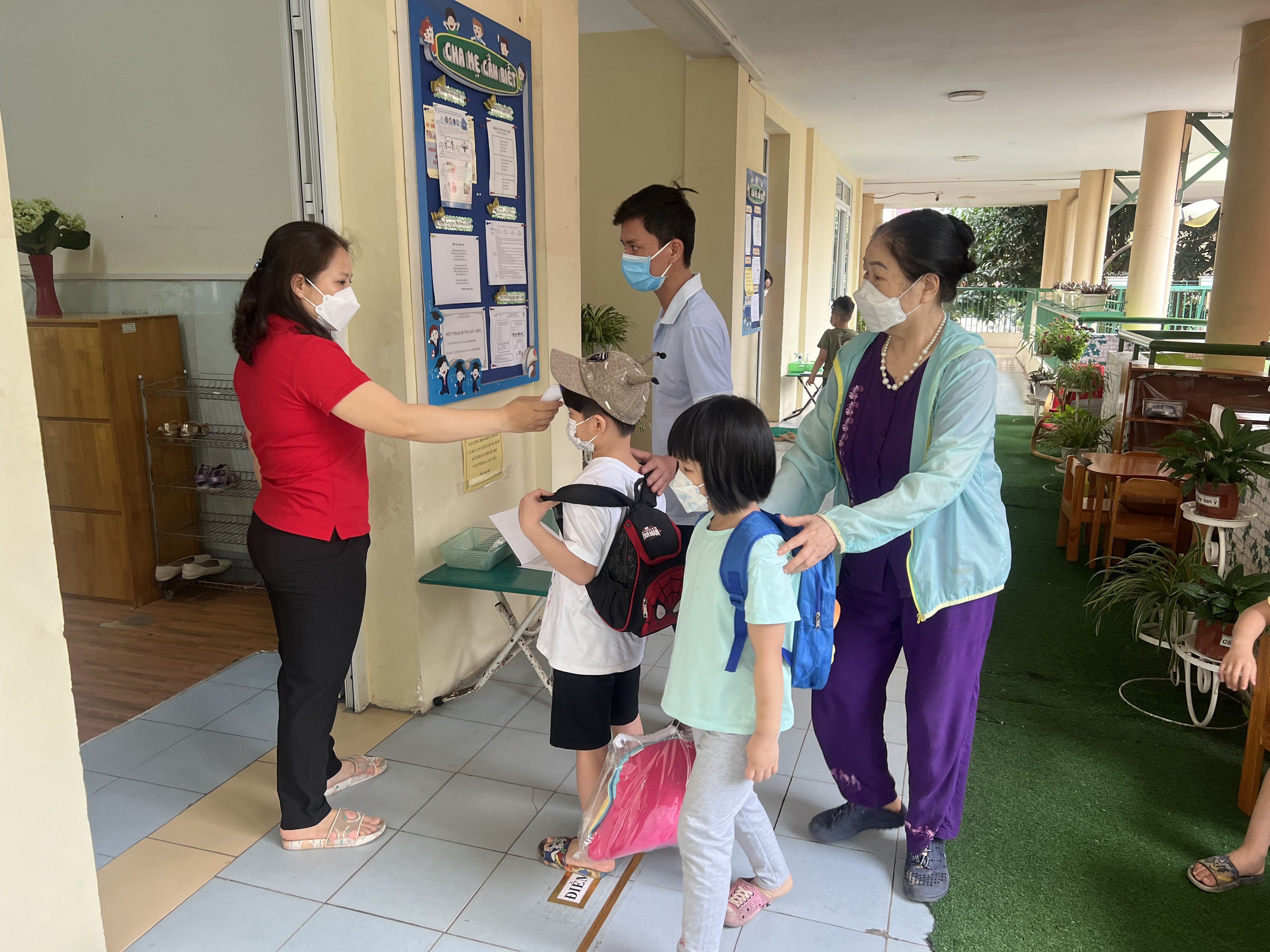 Cô Đào Thị Đức đo nhiệt độ, ân cần đón các con vào lớp mẫu giáo lớn A3.