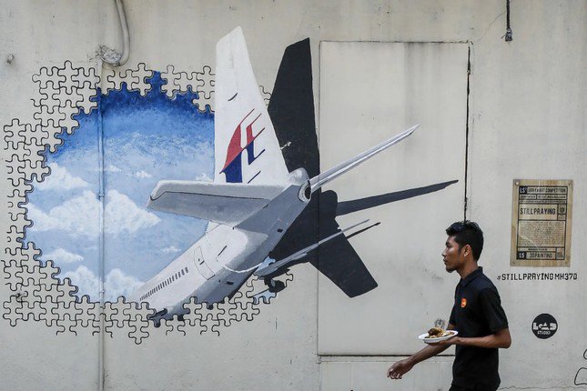 Một người Malaysia đi qua bức tường vẽ tranh tưởng niệm về MH370 tại thủ đô Kuala Lumpur vào năm 2016. Ảnh: AP.