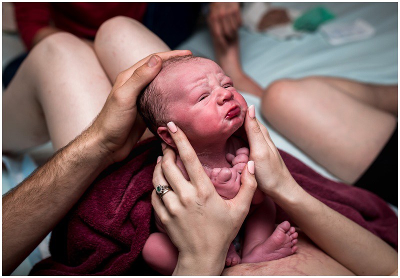 Em bé chu môi đầy giận dỗi dù được bàn tay mẹ âu yếm, chở che.
