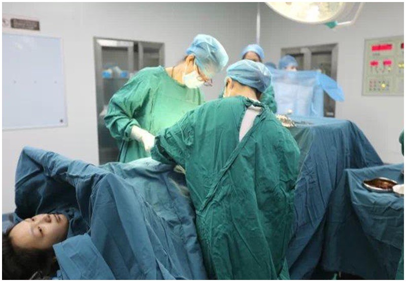 Các y bác sĩ tiến hành mổ đẻ cho sản phụ để đưa cặp song sinh chào đời an toàn. 
