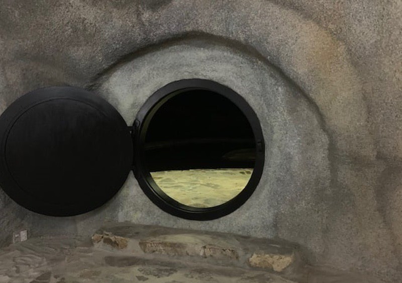 Lối vào hang đá là một cánh cửa hình tròn với viền đen sang trọng. Phía trên hang là một mái hiên được tạo thành từ các phiến đá chồng lên nhau.
