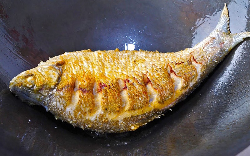Khi dầu nóng già, hạ lửa xuống mức vừa và nhỏ, rồi cho cá vào rán. Trong quá trình rán, không nên lật cá liên tục mà đợi mặt dưới vàng rồi mới lật. Khi nào cá chín, bạn tăng lửa một chút để dầu nóng hơn giúp cá vàng giòn hơn.
