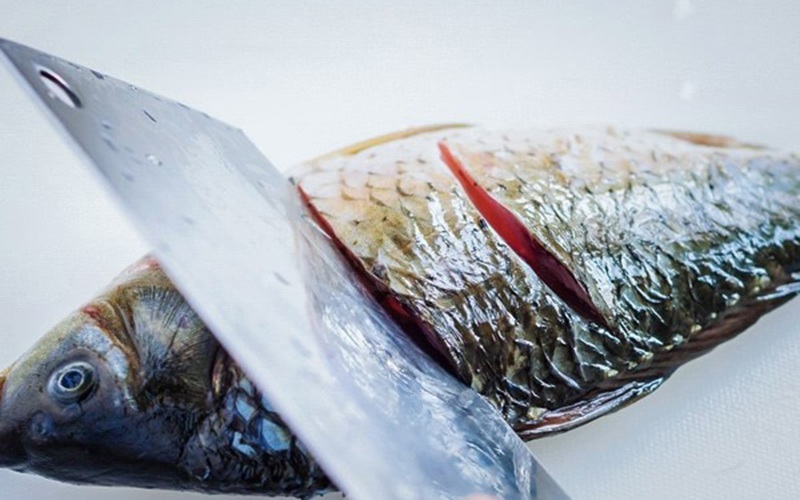 Nếu con cá bạn rán có kích cỡ to, thịt dày hãy dùng dao khứa khoảng 2-3 đường trên mình cá. Làm tương tự với mặt còn lại.
