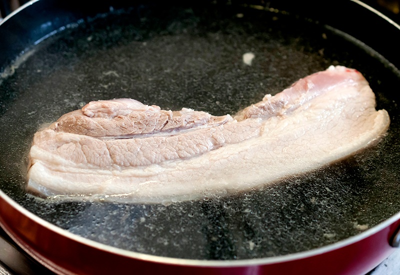 Chính hành và giấm sẽ là 2 nguyên liệu giúp bạn khử mùi hôi của thịt lợn, làm thịt lợn trắng hơn. Đun sôi nồi thịt rồi hạ nhỏ lửa, luộc liu riu đến khi thịt chín. Thời gian thịt chín phụ thuộc vào khối lượng miếng thịt.
