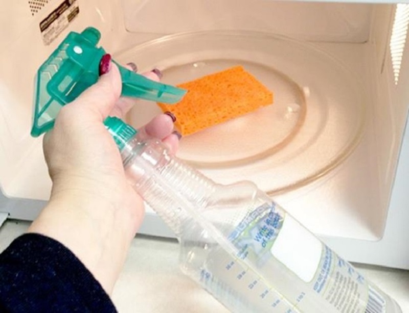 Using glass cleaner to clean the microwave