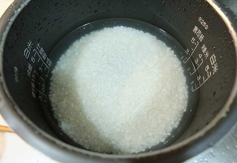 Sau khi vo gạo xong, hãy để ráo nước rồi cho vào nồi. Lúc này trộn thêm 5g dầu thực vào sau đó thêm nước vào nấu cơm. Bằng cách này, hạt cơm trong, bóng hơn thì khi rang cũng ngon và hấp dẫn hơn nhiều.
