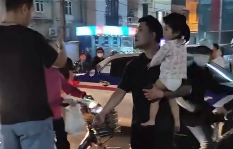 Người đàn ông bế theo bé gái, chặn đầu phương tiện trên đường. Ảnh: Dân Việt