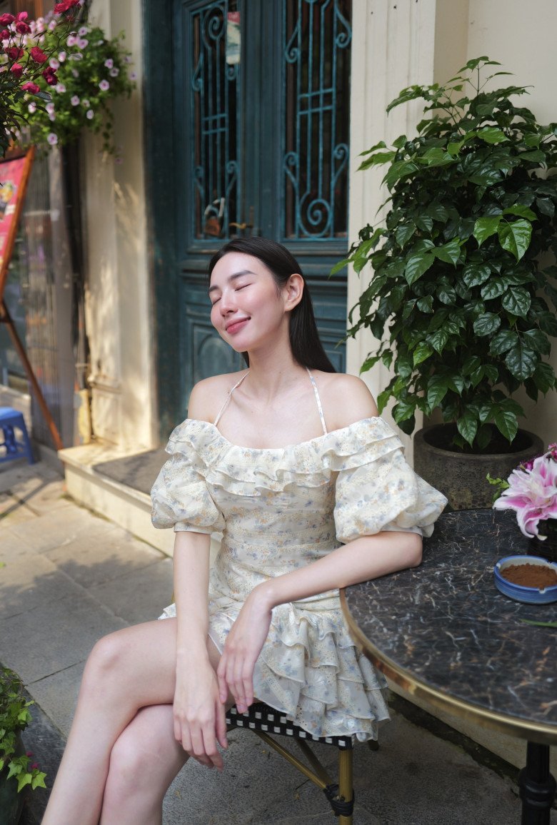 Hoa hậu Thùy Tiên xuống phố cà phê với bạn bè cùng chiếc váy hoa nhí có gam màu trang nhã. Thiết kế xếp bèo nhún buộc dây giúp Hoa hậu tôn phần xương quai xanh.