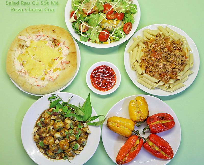 Bánh Pizza cua, salad, nui sốt bò băm, trứng cút lộn xào me, ớt ngọt nhồi thập cẩm.
