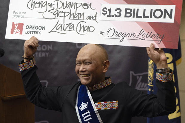 Cheng Saephan giơ tấm séc lên sau khi phát biểu trong cuộc họp báo tại trụ sở Xổ số Oregon.