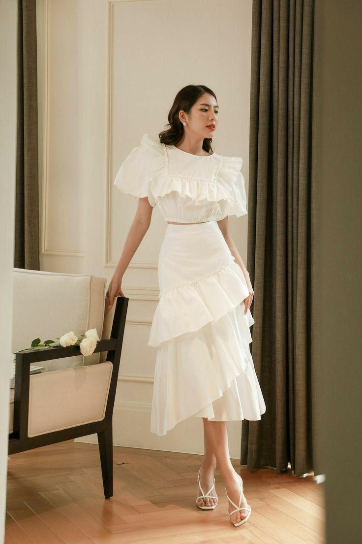 Chân váy trắng xếp tầng phối cùng áo kiểu trắng và giày cao gót mang đến sự sang trọng quý phái