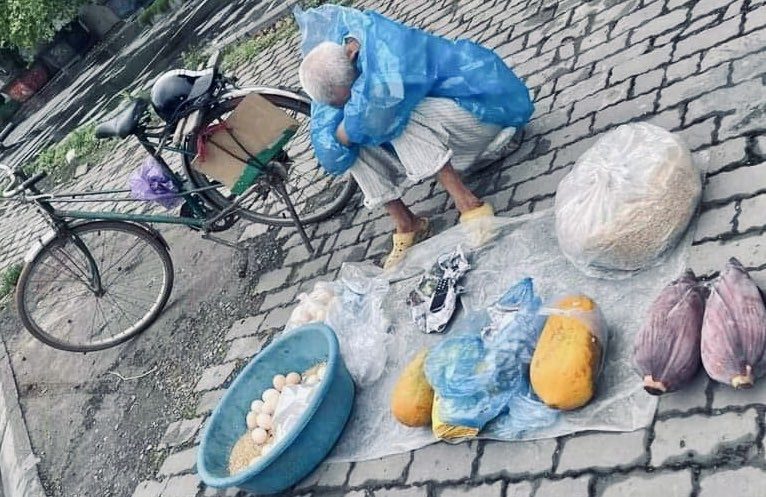 Hình ảnh cụ Đan ngồi co ro trong cơn mưa Hà Nội sáng 10/5 khiến những người đi đường cảm thấy xót xa