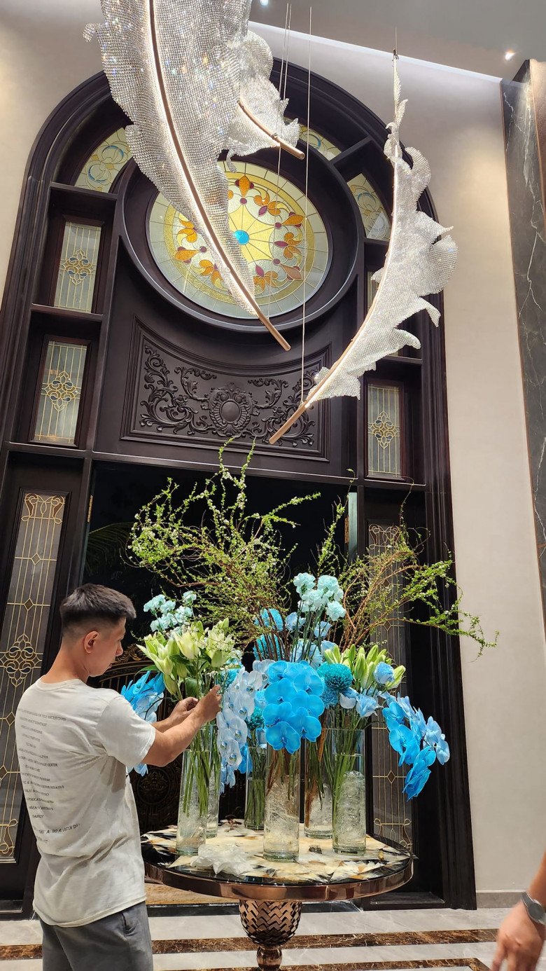 Hàng loạt những chiếc bình trong suốt  được trang trí bằng những bông hoa màu xanh dương tươi tắn, kết hợp với các loại cây cành dài, tạo nên một sự phối hợp hài hòa đầy nghệ thuật.