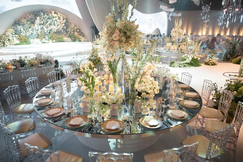 Bàn ăn được trang trí với hoa tươi gam trắng. Mỗi bàn tiệc phục vụ gần 20 quan khách. Menu được đặt sẵn trên bàn.