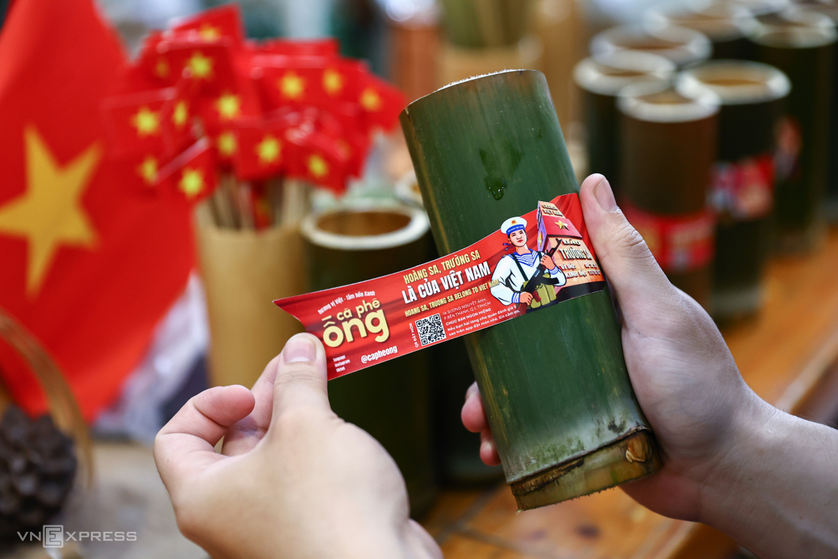 Ngoài đính cờ, quán dán thêm sticker hưởng ứng 50 năm ngày thống nhất đất nước lên ống tre.